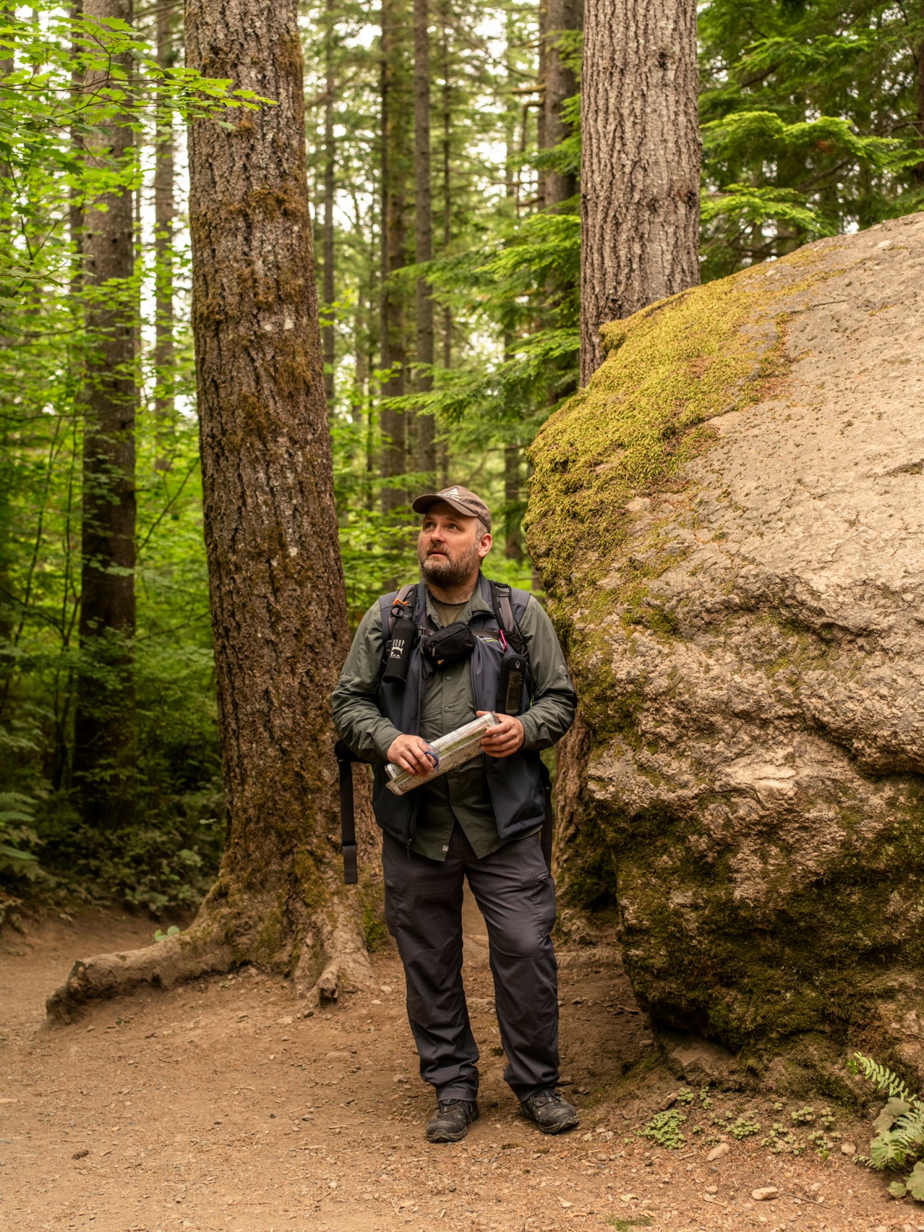 Chuck Kitterman, chief cartographer at Green Trails Maps, holds a paper map while hiking on a forest trail.