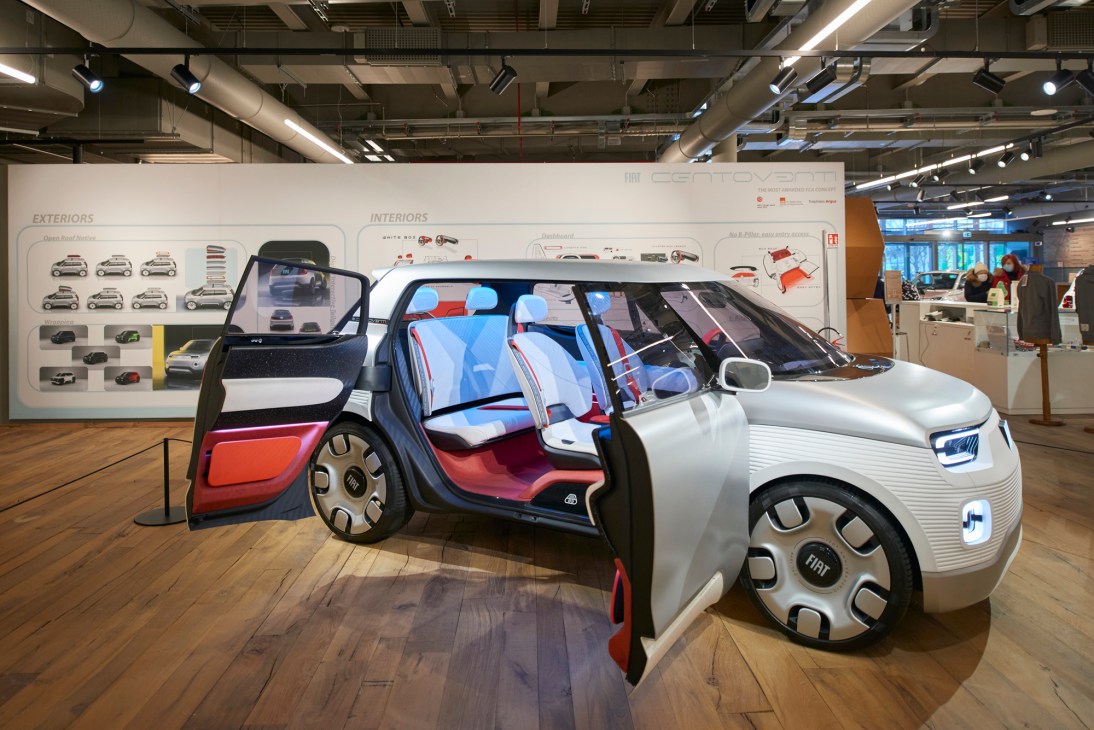 White and silver Fiat concept car with open doors displaying colorful interior in modern showroom