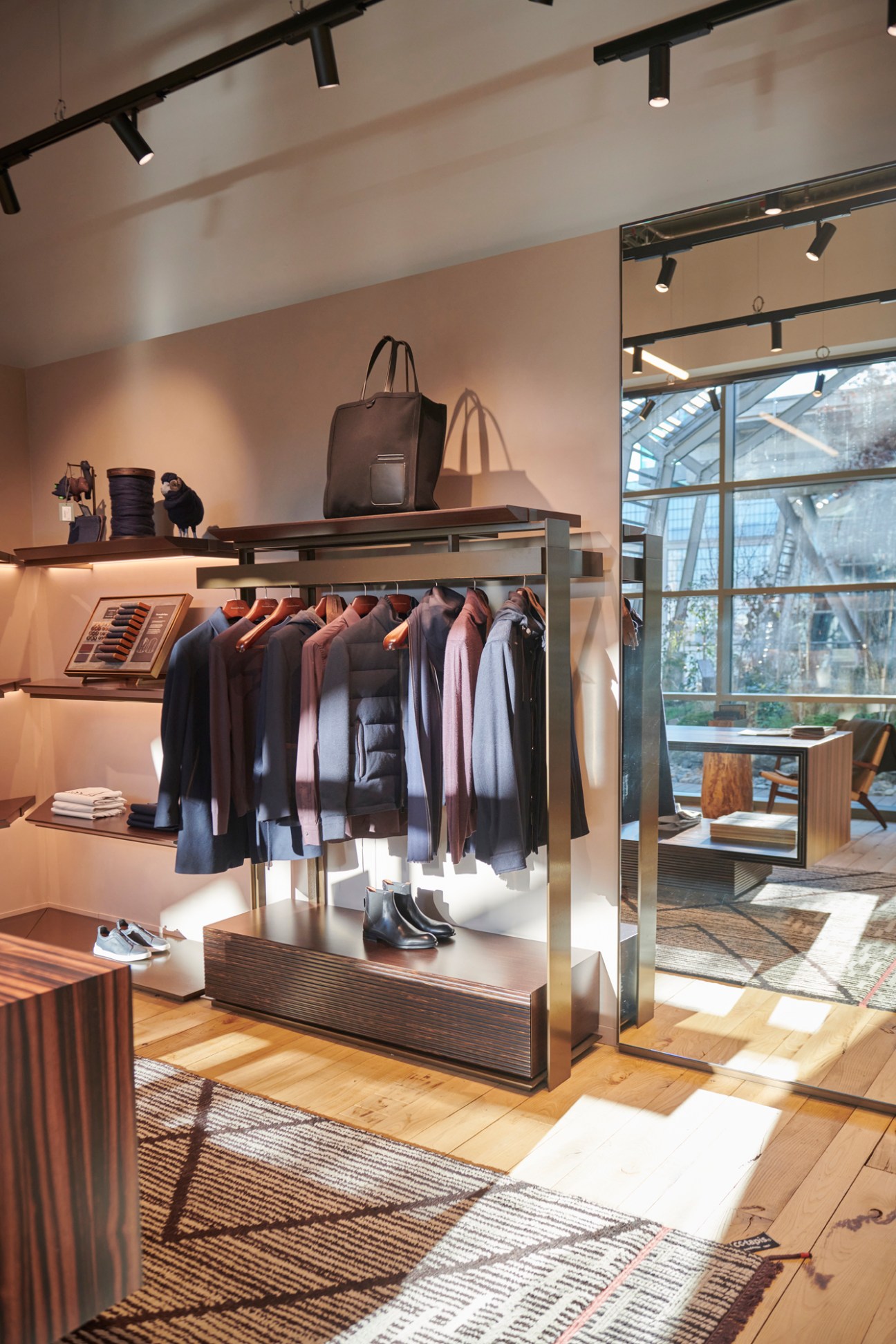 Zegna store interior with clothing rack displaying jackets and blazers, bags on upper shelf