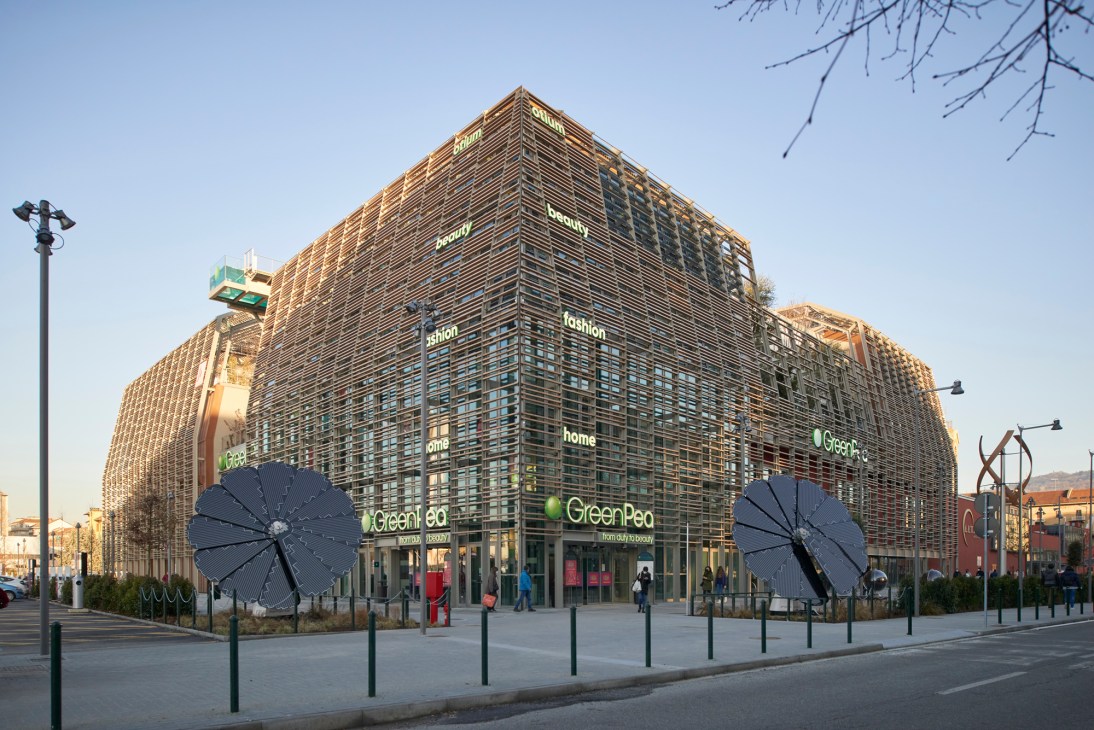 Modern building with distinctive wooden lattice facade and large solar panel installations at entrance