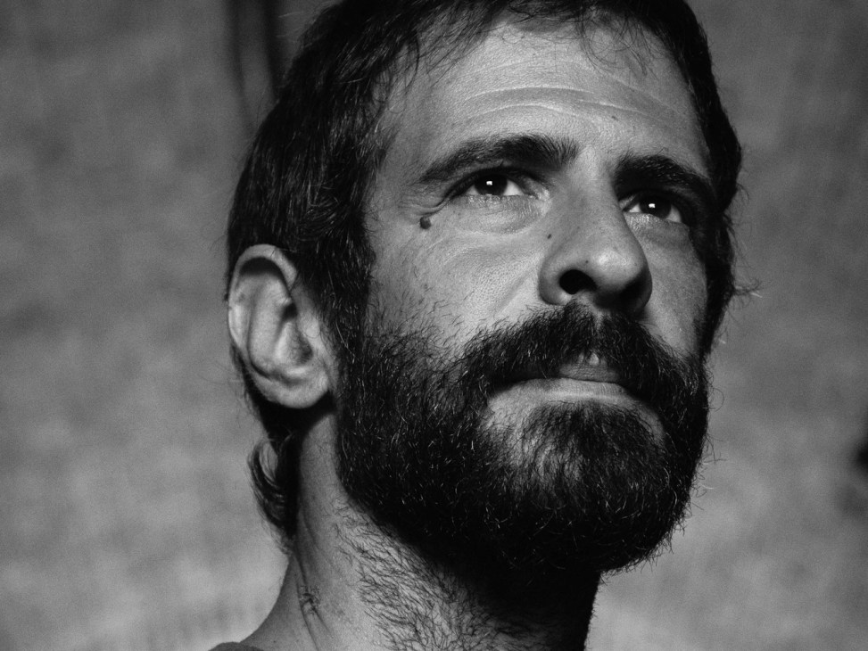 Portrait of Giulio Rubino, Italian crime reporter, looking upward in black and white