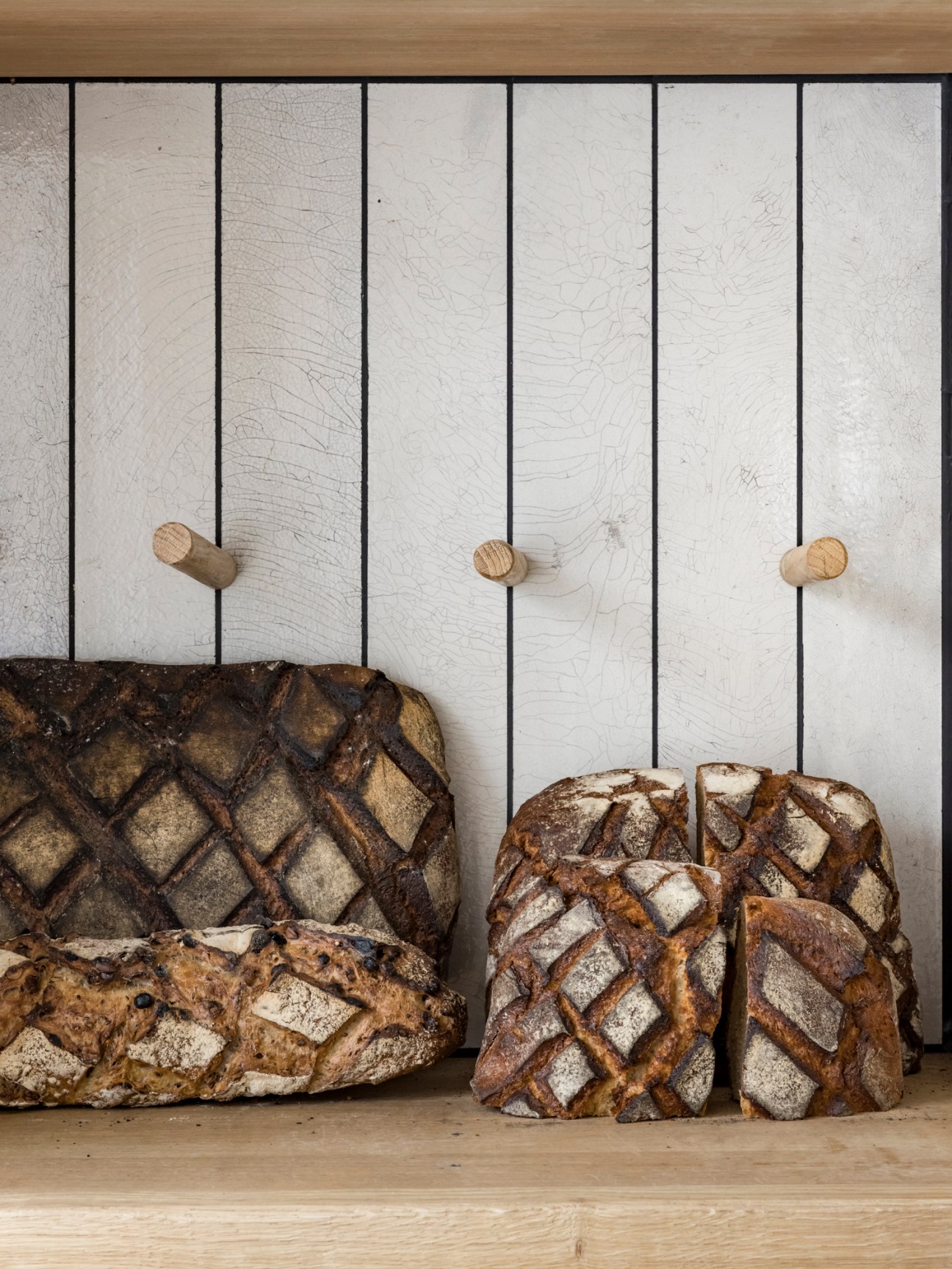 Artisanal sourdough bread loaves with decorative scoring patterns displayed on wooden shelves