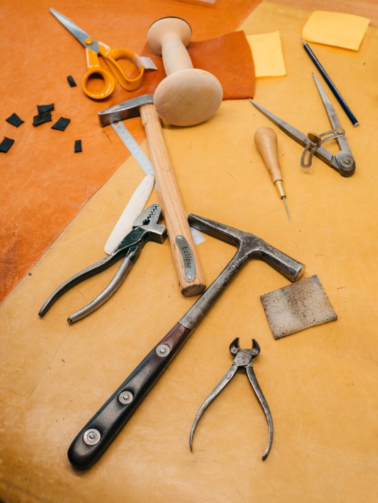 Collection of leather-working tools arranged on an artisan's workbench