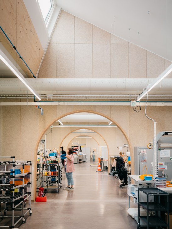 Spacious factory interior with high ceilings and natural light from arched windows