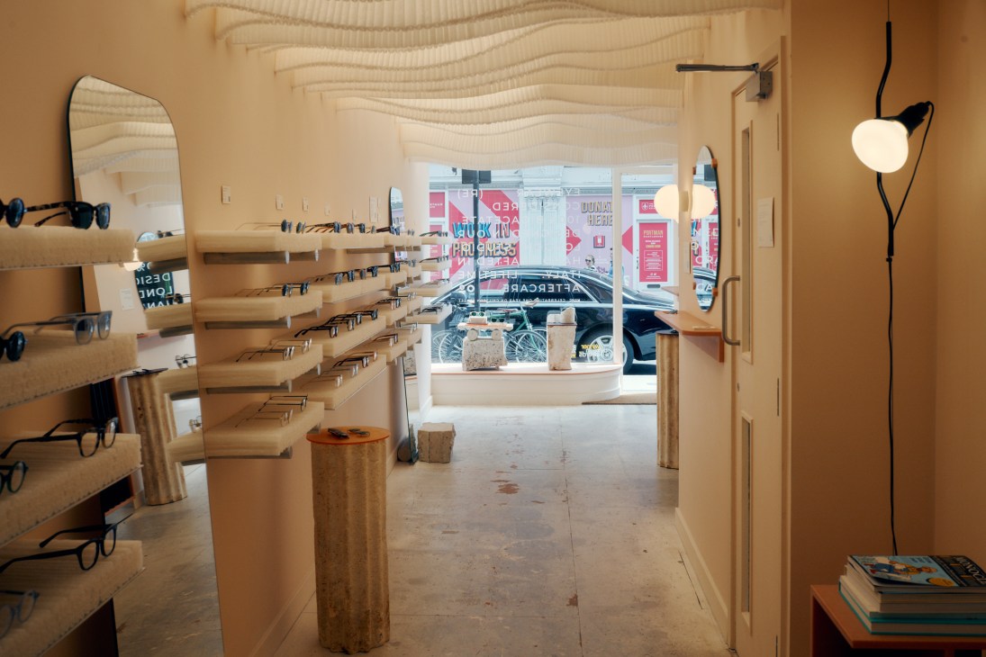 Interior view of Monc eyewear shop showing wooden display shelves with eyeglasses, mirror, and modern lighting