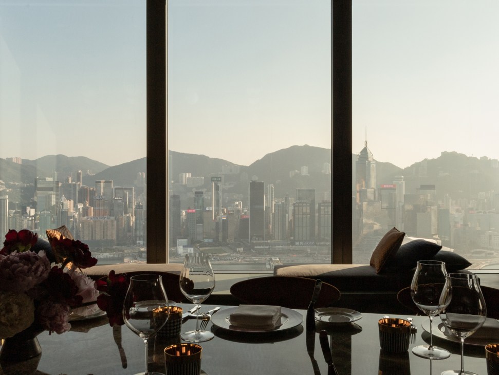 Elegant dining table setup at Carlyle & Co with panoramic Victoria Harbour and Hong Kong skyline views through windows