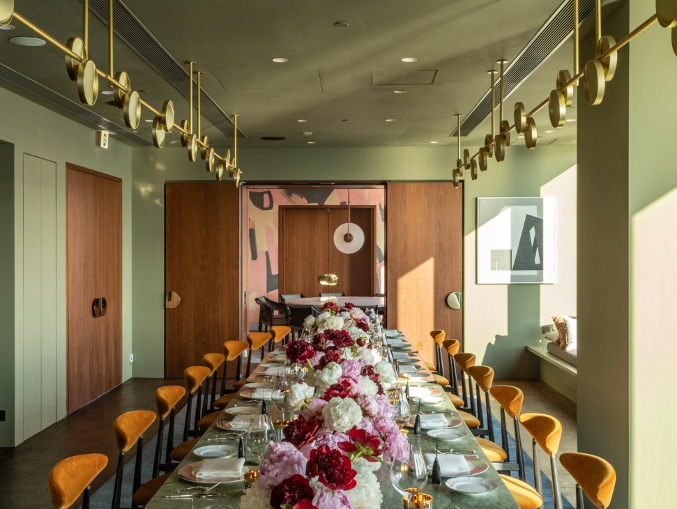 Modern dining room with long table, orange chairs, floral centerpiece, and panoramic windows