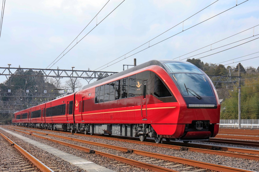 Red and grey Hinotori express train on railway tracks with overhead power lines