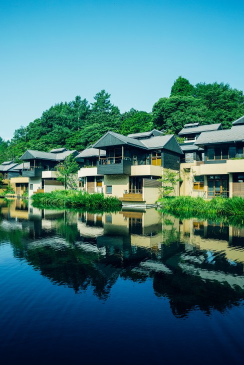 Hoshinoya Karuizawa ryokan with modern architecture reflected in a pond surrounded by lush greenery.