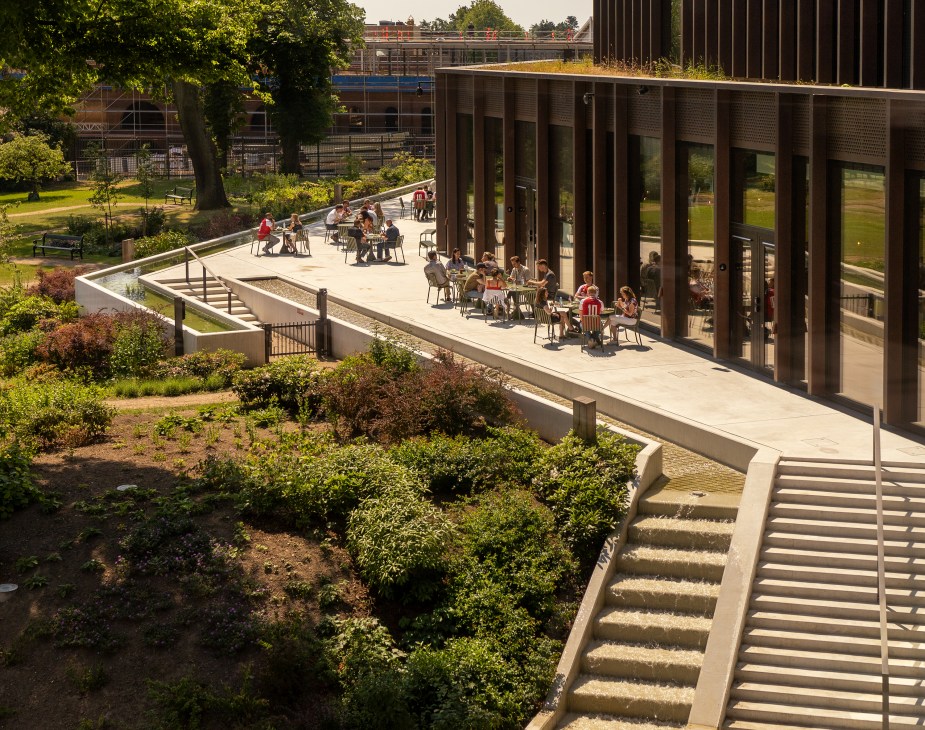 Outdoor dining terrace with employees seated at tables under modern building overhang