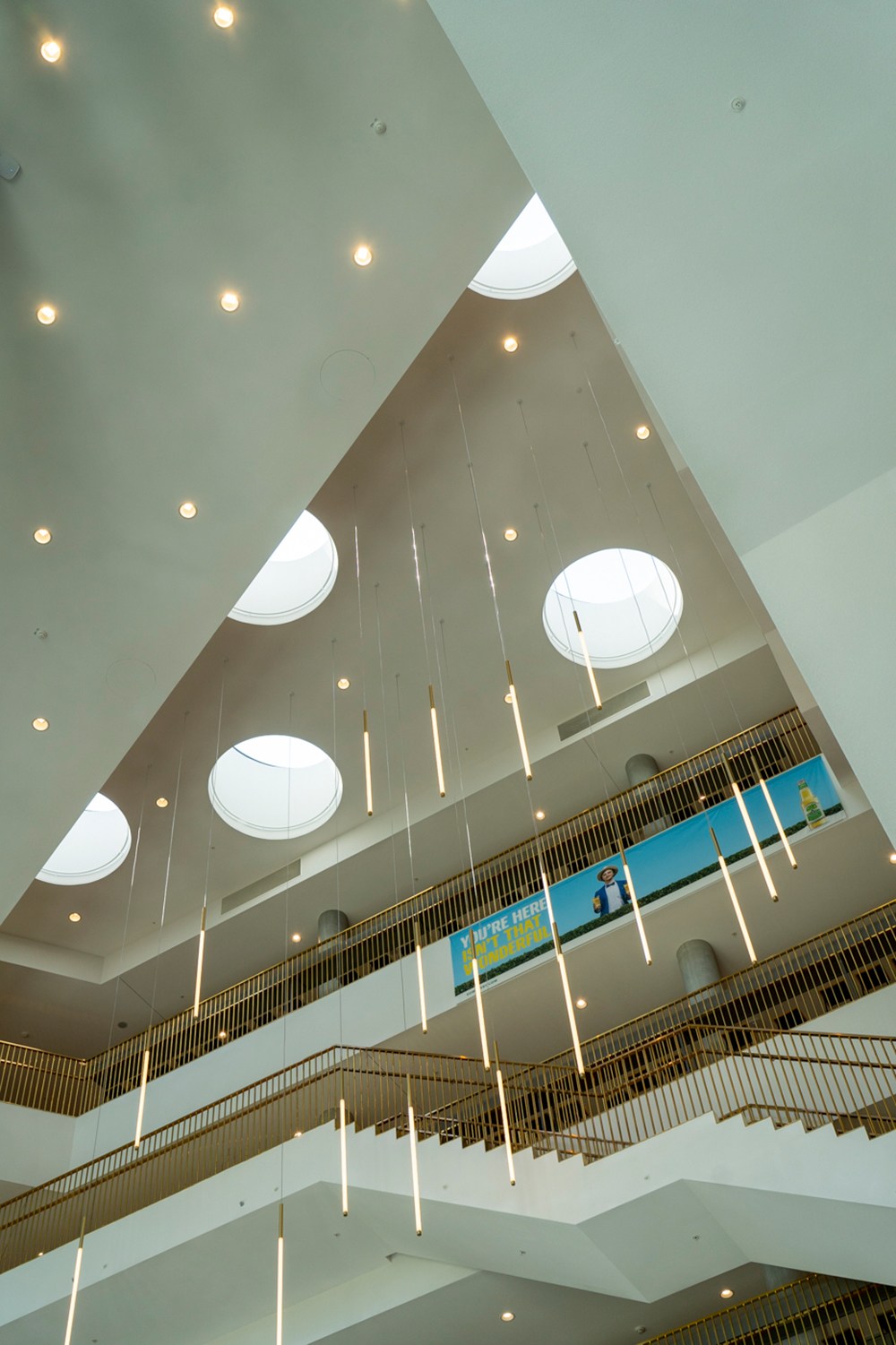 Interior view of modern office atrium with multiple levels, pendant lighting, and circular skylights