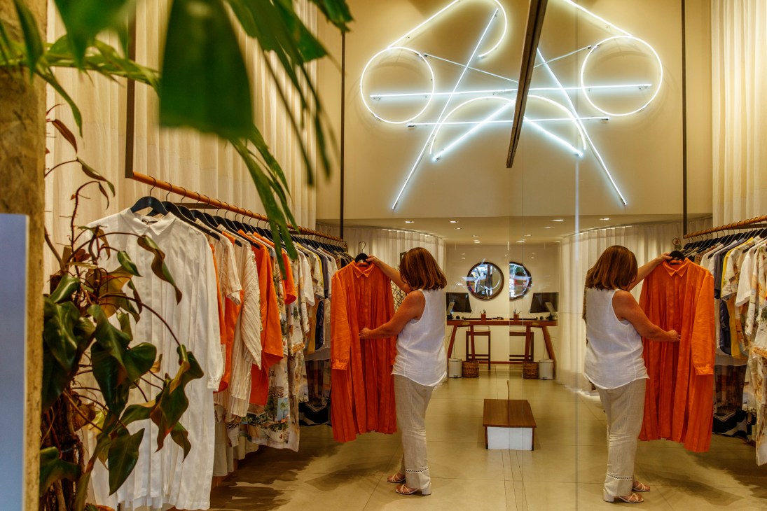 Handred shop in Ipanema with woman browsing orange clothing on racks under modern lighting