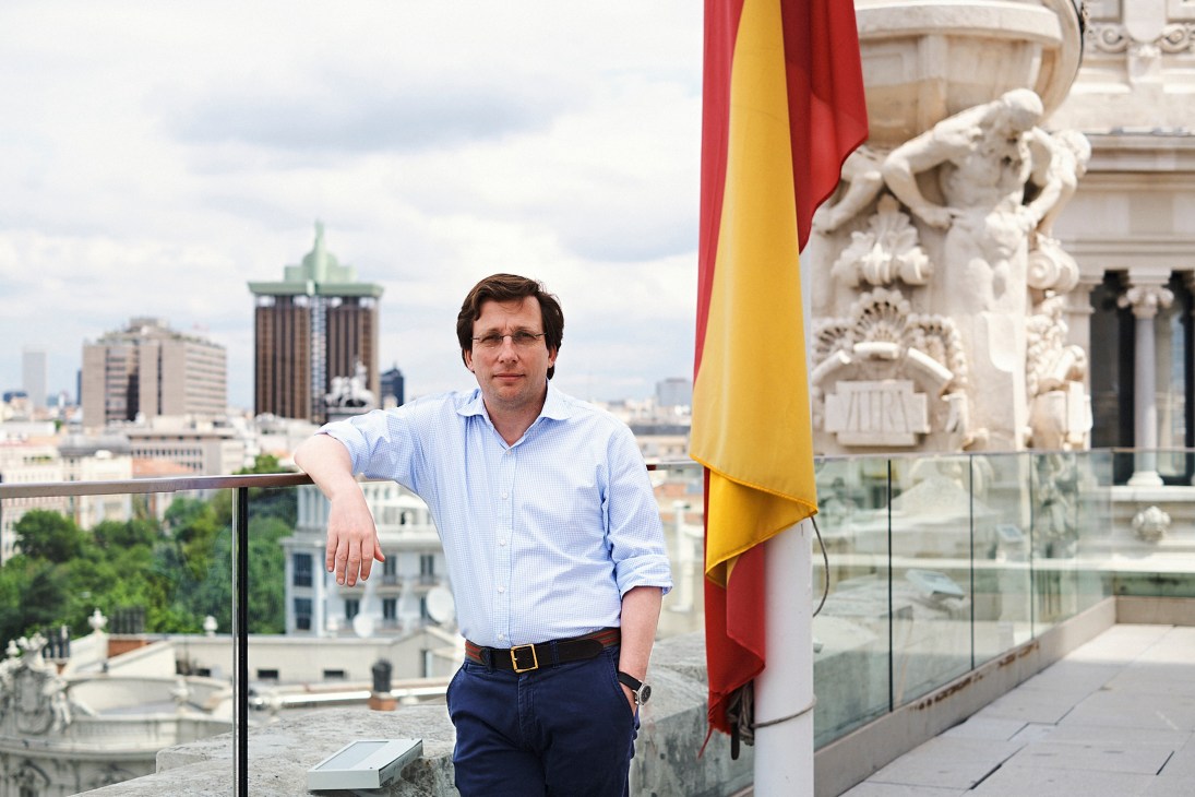José Luis Martínez-Almeida stands on a balcony with Spanish flag and ornate architecture in background