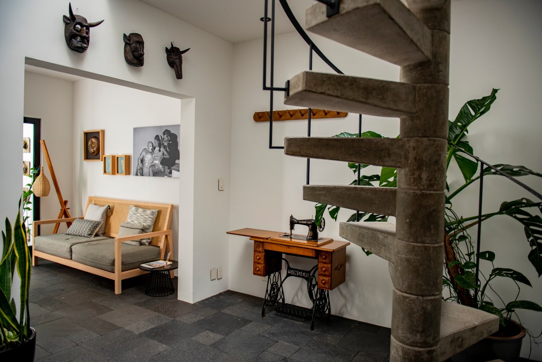 Modern interior with concrete stairs, vintage sewing machine, wooden furniture and decorative masks on white walls