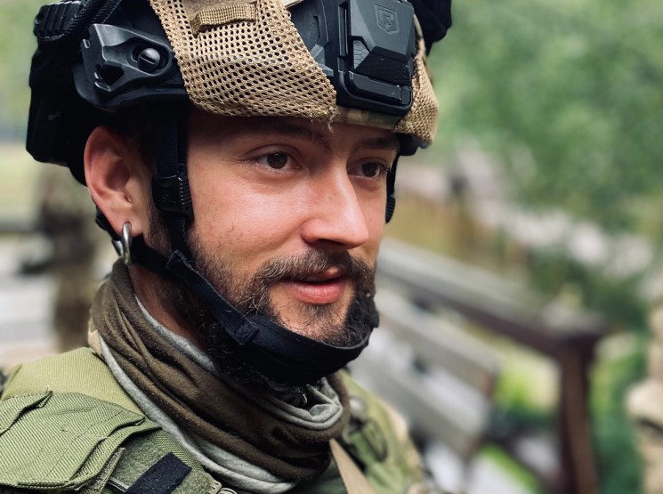 Ukrainian soldier in military fatigues wearing tactical helmet with night vision goggles mounted on front.