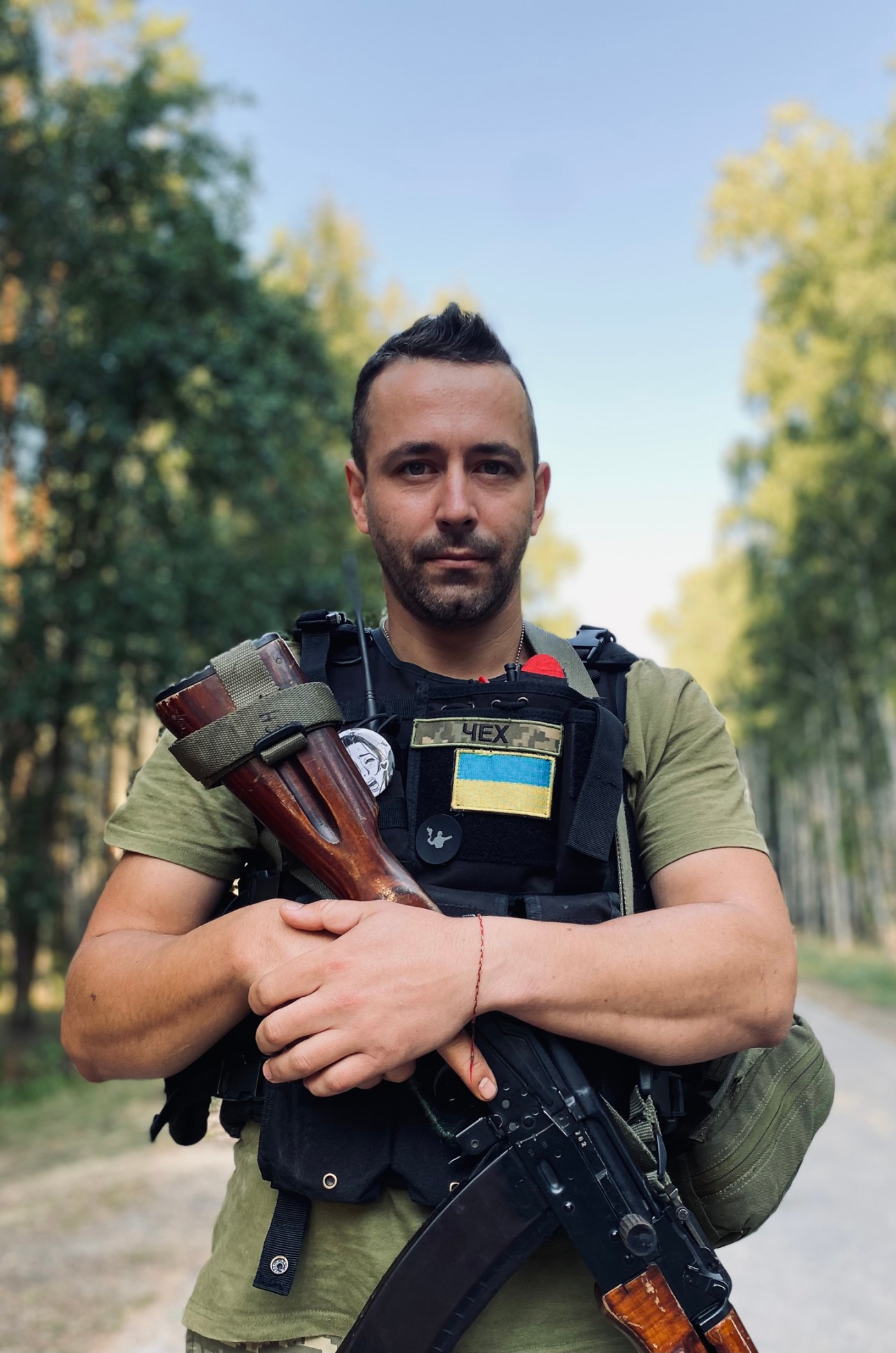 Ukrainian reservist 'Chekh' in military gear holding ammunition in a forest setting.
