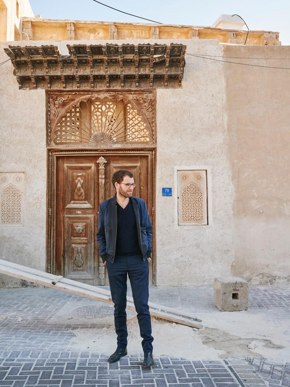 Architect Anne Holtrop standing outside traditional Middle Eastern building with ornate wooden door in Bahrain