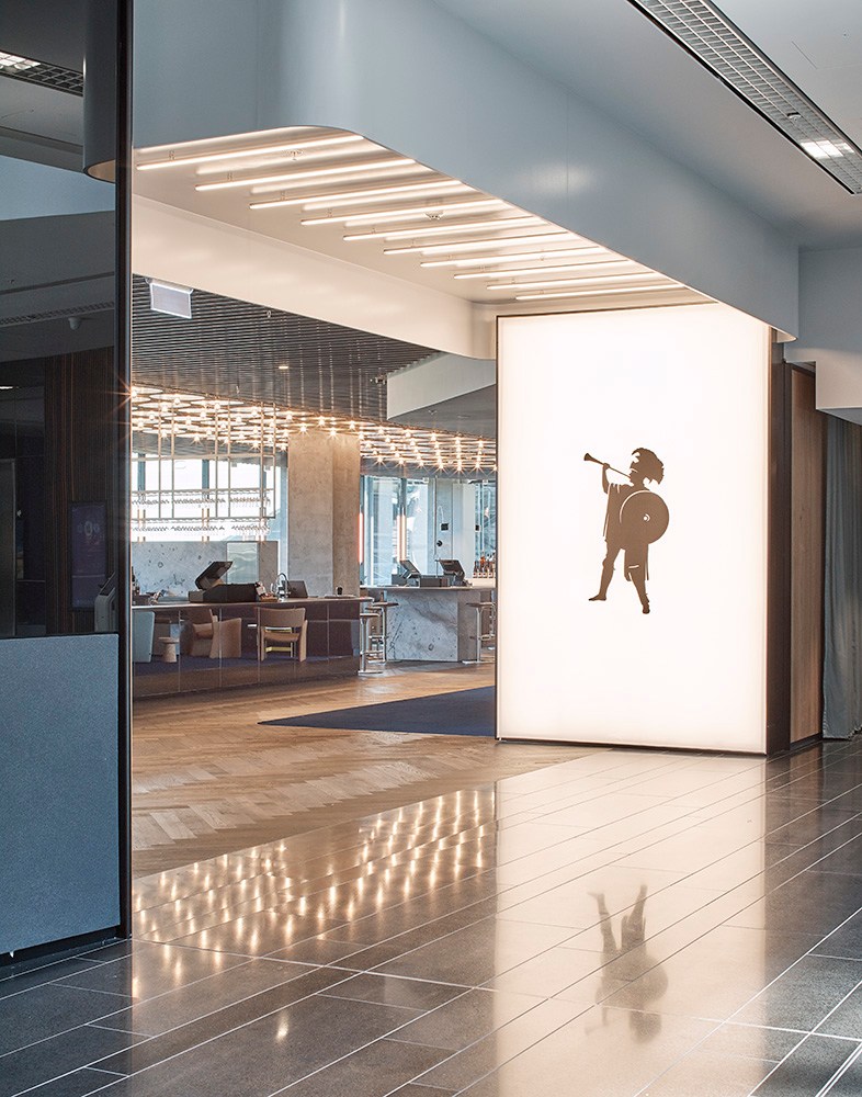Modern restaurant or hotel entrance featuring sleek architecture with illuminated ceiling and silhouette figure on wall