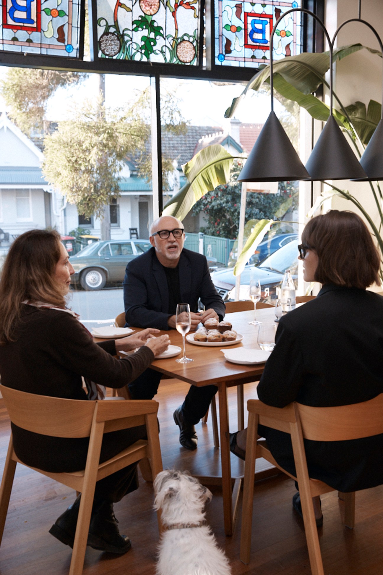 Three people sitting around a wooden table having drinks and conversation in a modern restaurant setting