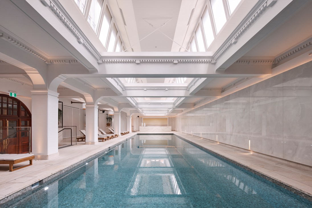 Elegant indoor swimming pool with white columns, skylights, and classical architectural details