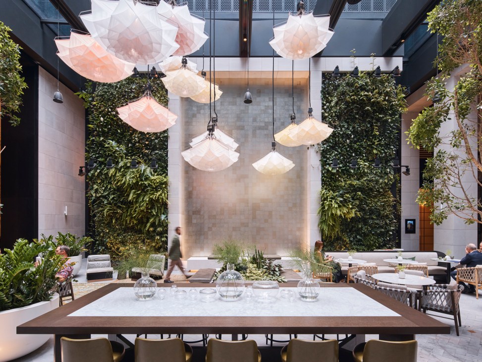 Aperture courtyard with suspended flower-like lights by Studio Drift, dining tables, and living green walls