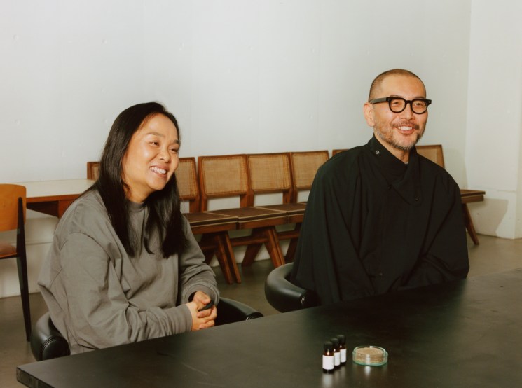 Hideaki Yoshihara and Yukiko Ode, founders of Hyke, sitting at a dark table in their Tokyo design studio