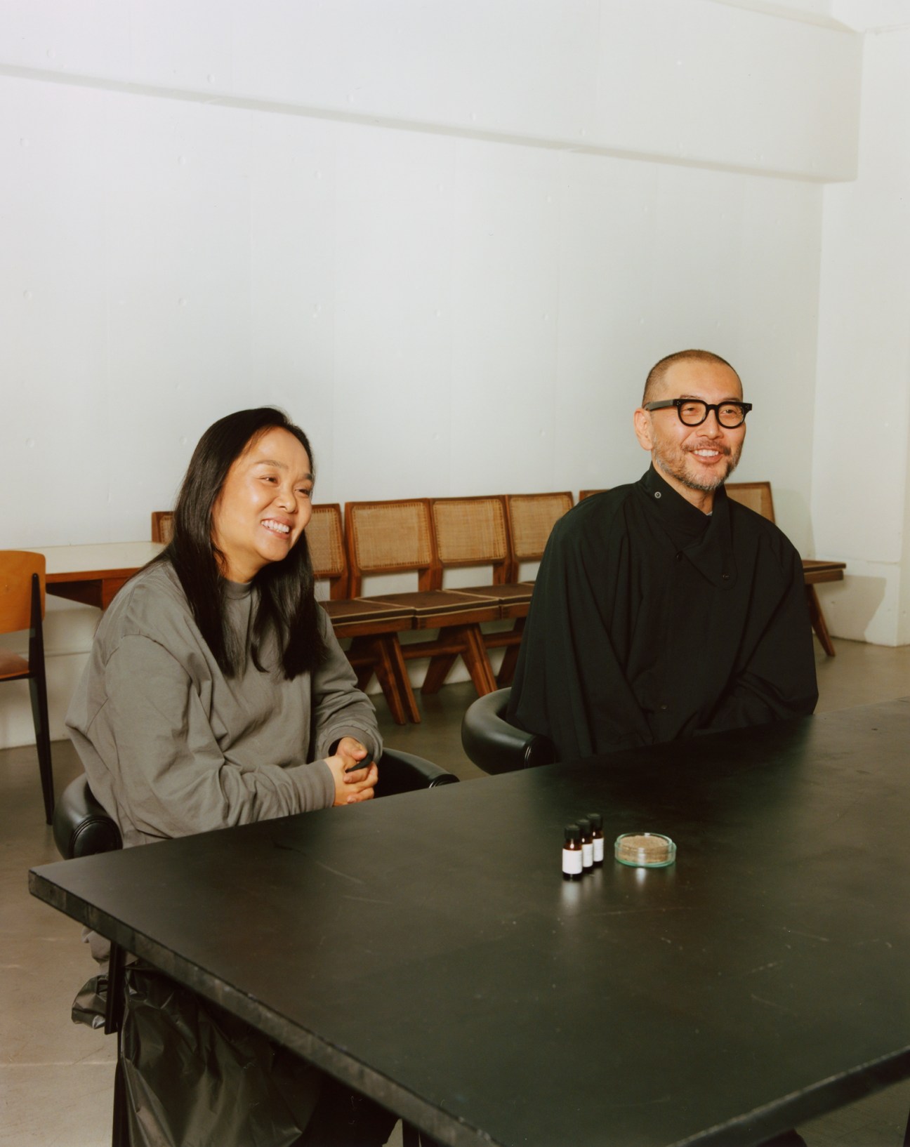 Hideaki Yoshihara and Yukiko Ode, founders of Hyke, sitting at a dark table in their Tokyo design studio