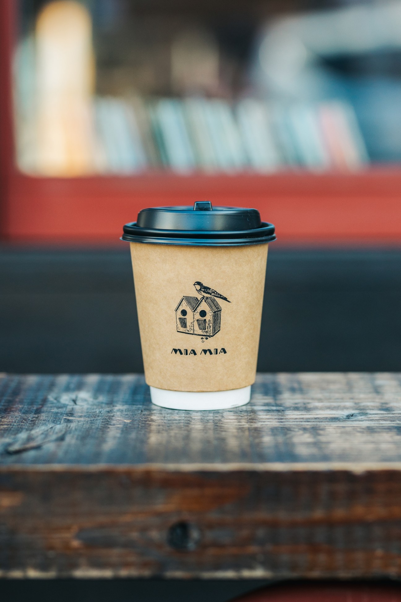 Mia Mia branded coffee cup with birdhouse logo on wooden table