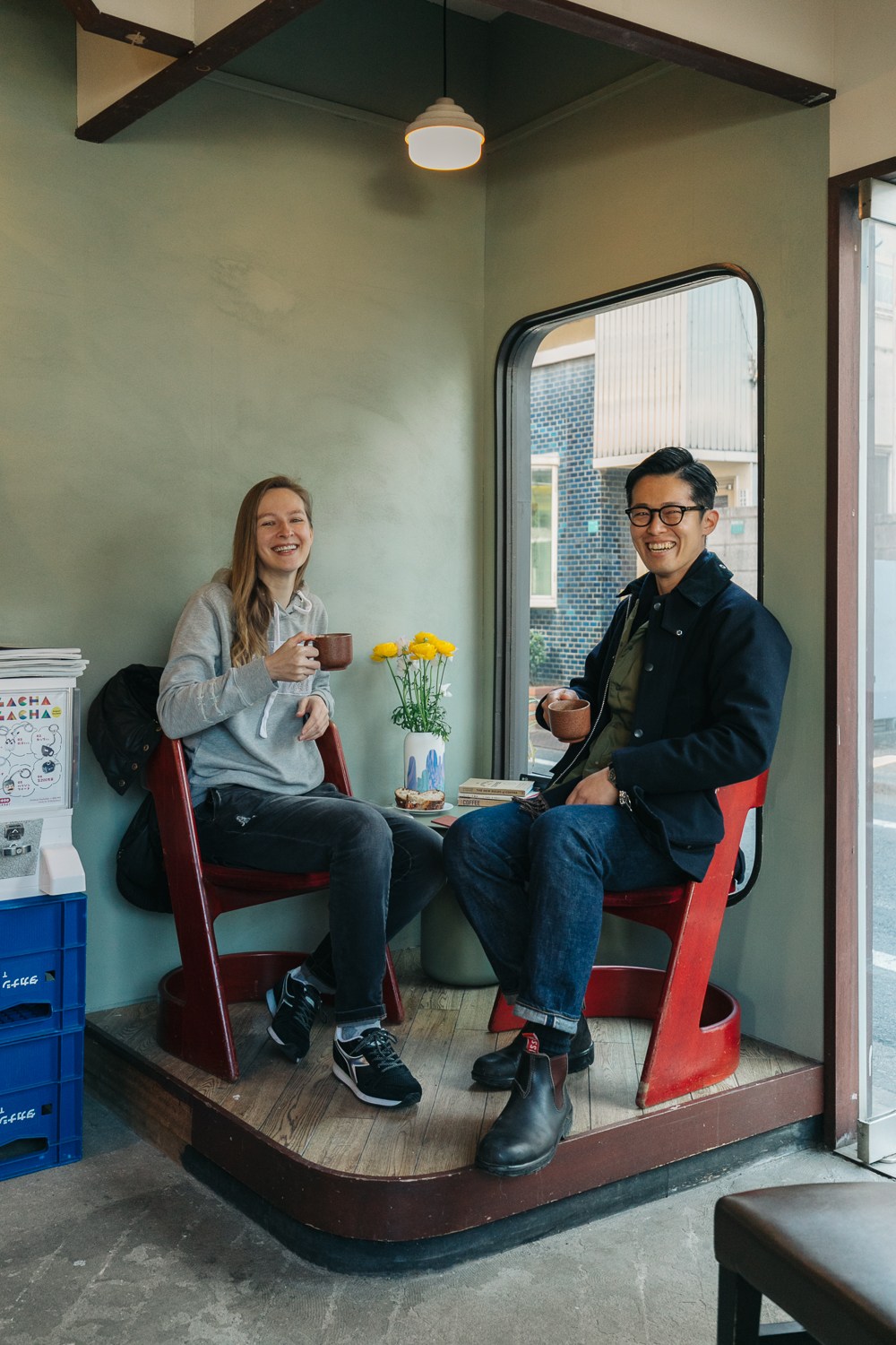 Two people sitting in red chairs enjoying coffee in a cozy interior space