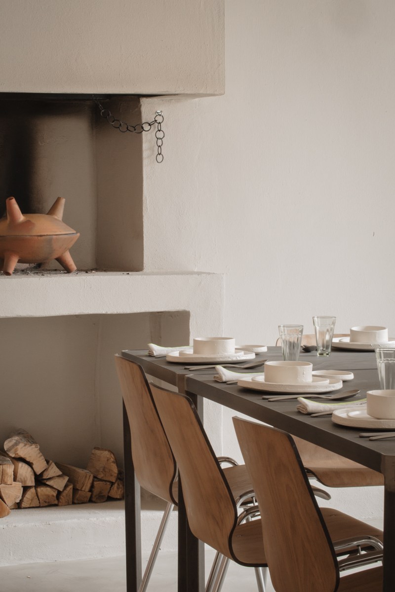 Minimalist dining room at Altatto restaurant with set table, wooden chairs, and neutral tones.