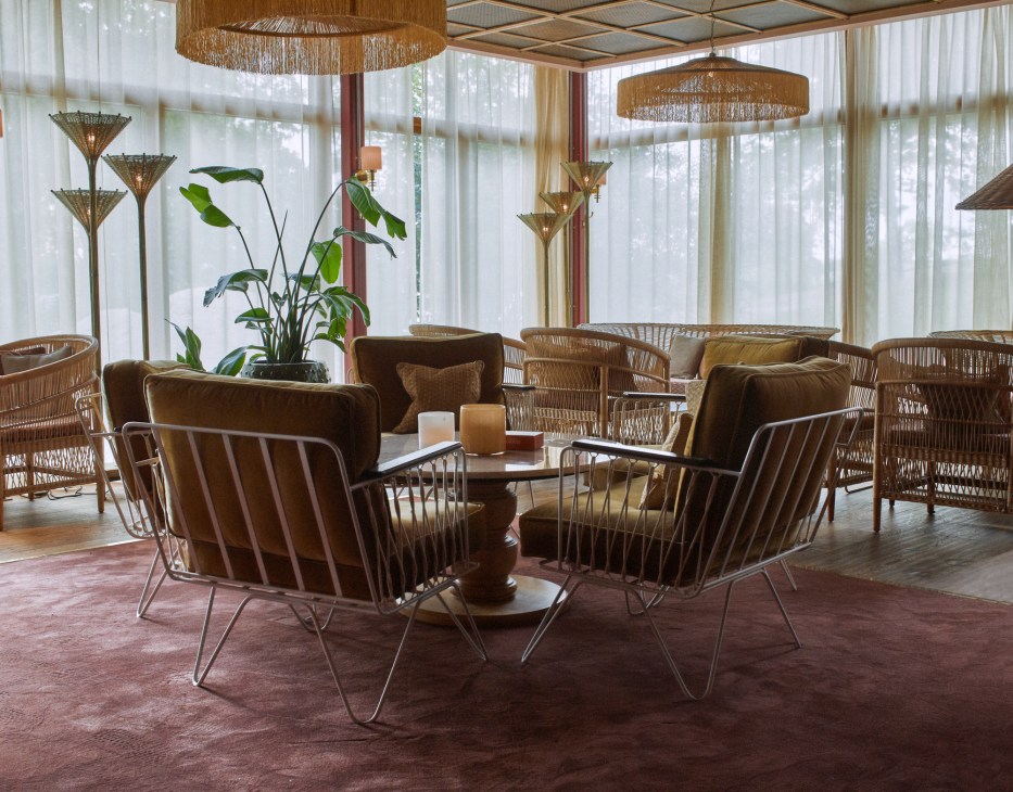Modern hotel lounge with wicker chairs, fringe pendant lights, and large windows
