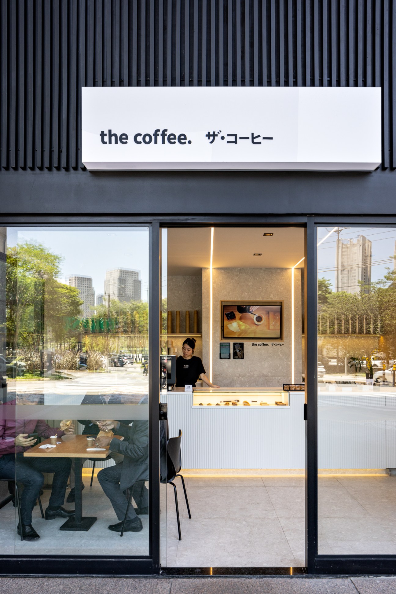Modern coffee shop storefront with Japanese-style signage reading 'the coffee' and glass windows showing interior counter