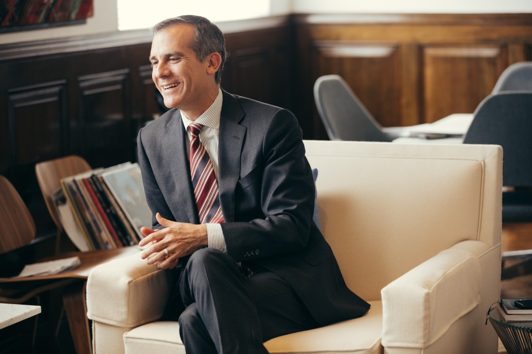 Man in business suit and striped tie sitting on cream-colored sofa in an office setting.