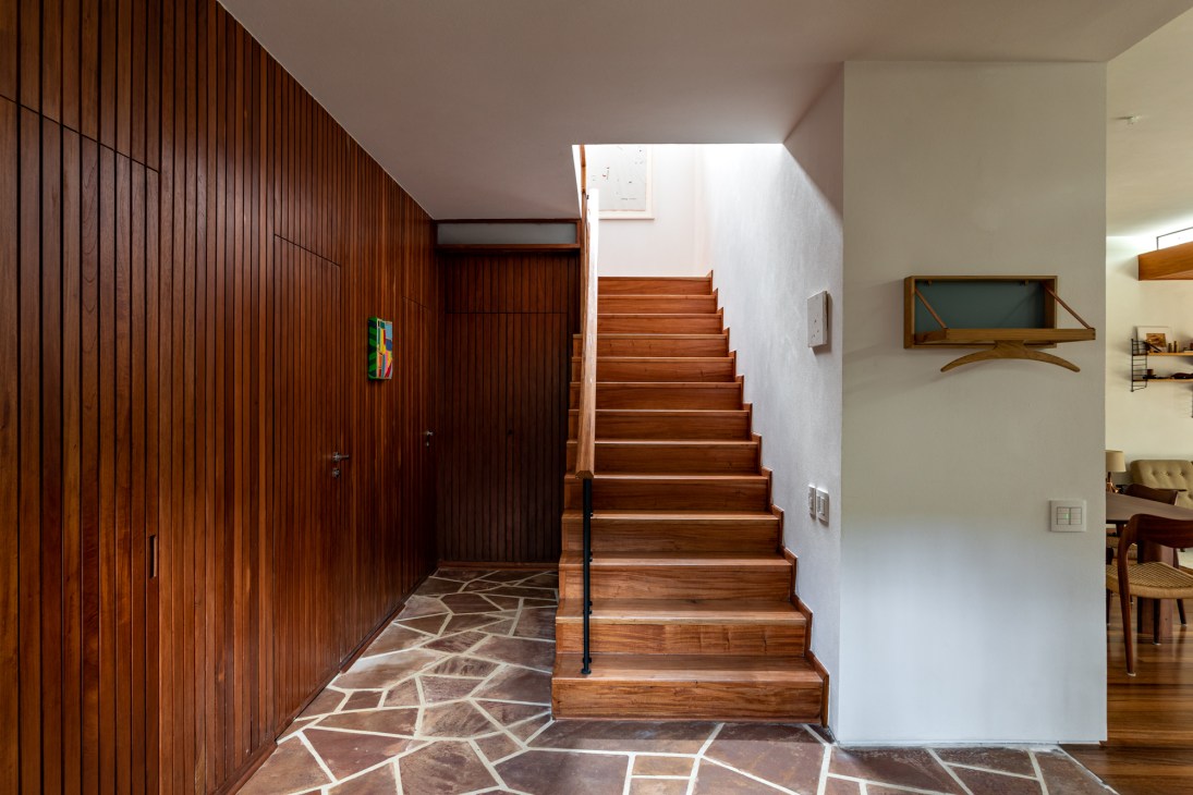 Modern entryway with vertical wood paneling, wooden staircase, and geometric stone floor pattern