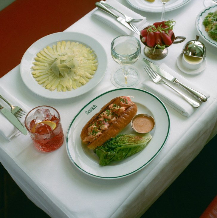 Elegant table setting at Bostich restaurant featuring lobster roll, sliced fennel salad, and cocktails