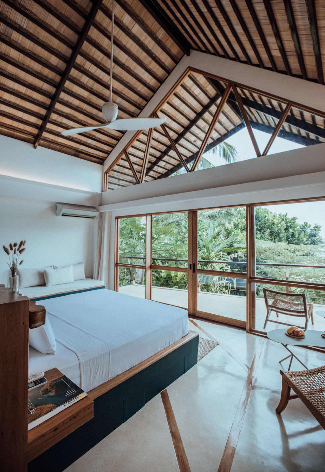 Modern tropical bedroom with exposed bamboo ceiling, wooden furniture, and sliding glass doors to balcony