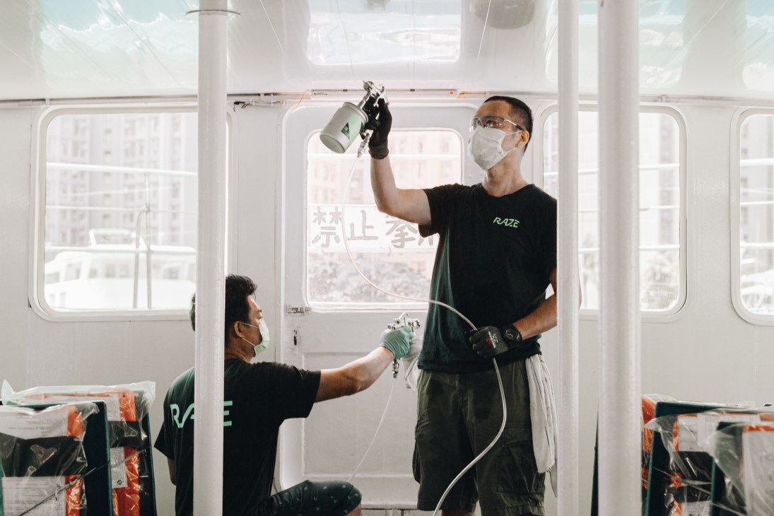 Two workers in protective masks spray an antimicrobial coating inside a retail shop in Hong Kong for Raze.