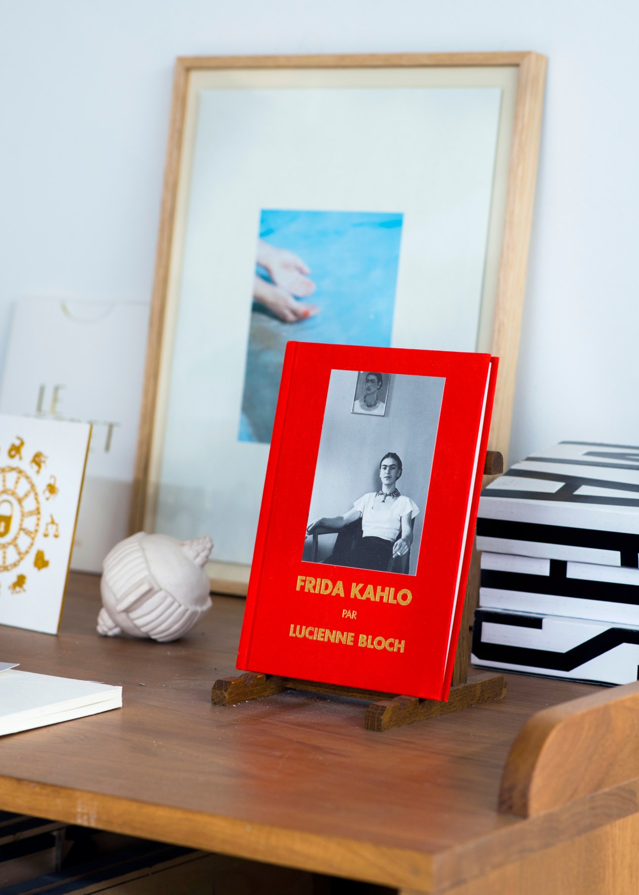 Interior view of Imprimerie du Marais with wooden desk, framed artwork, books, and red Frida Kahlo biography by Lucienne Bloch