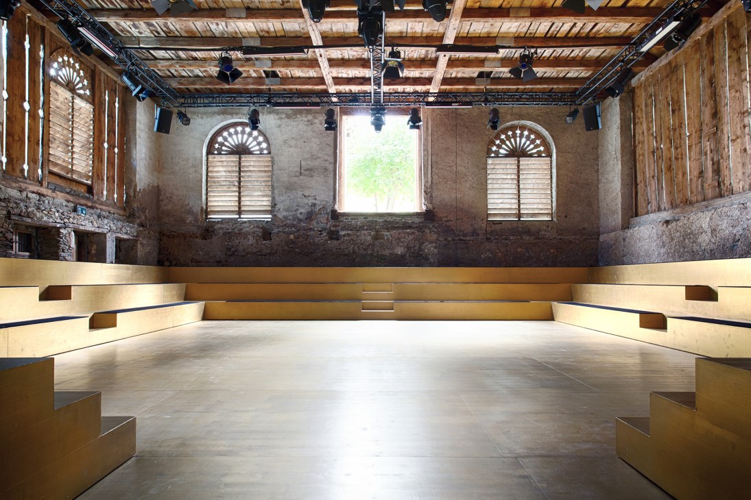 Modern theater interior with tiered wooden seating surrounding a circular performance space