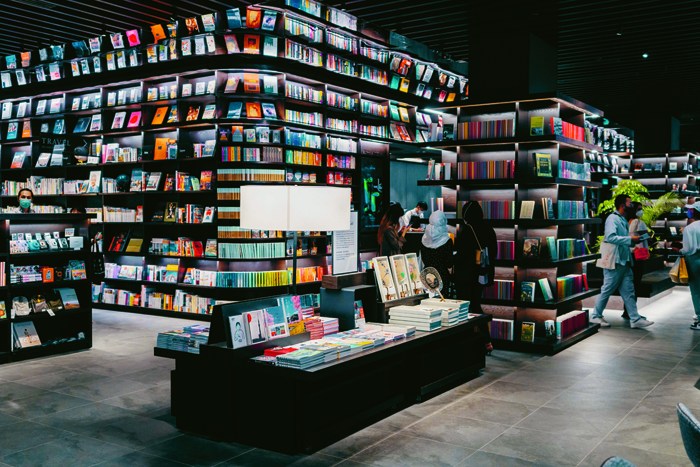 Modern bookstore interior with floor-to-ceiling shelves filled with colorful books and customers browsing