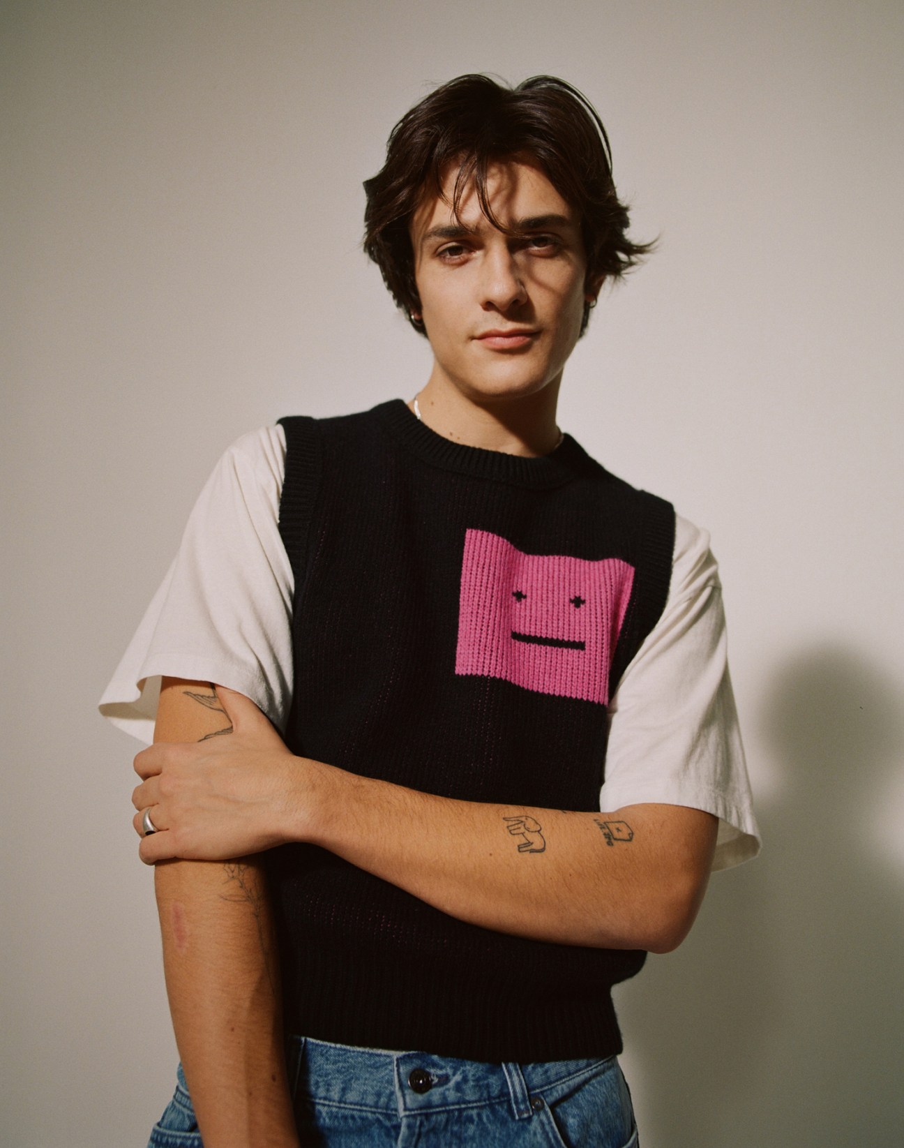 Portrait of French DJ Kungs wearing a black knit vest with pink face design over white t-shirt