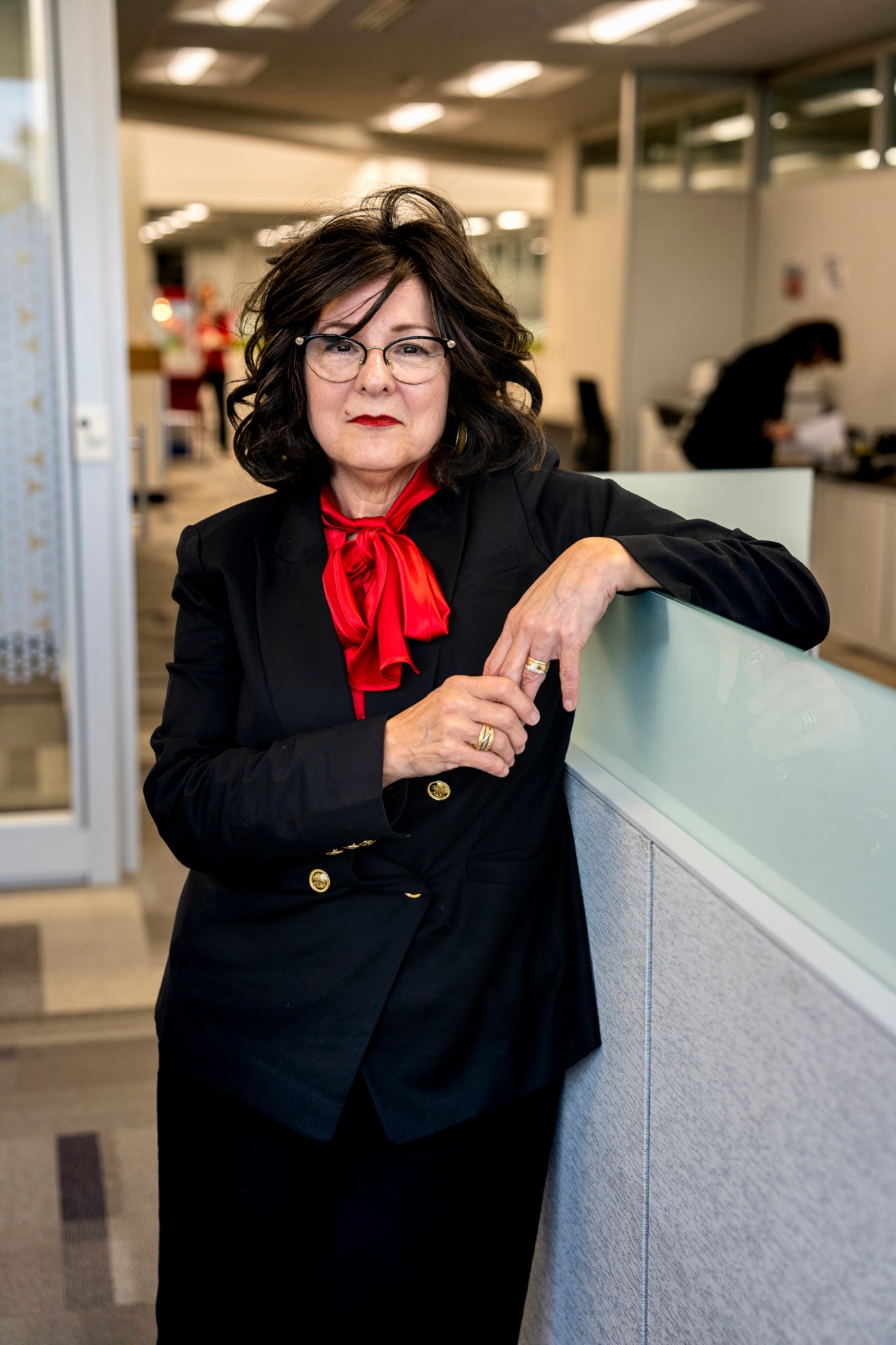 Debi Durham, director of the Iowa Economic Development Authority, poses for a portrait in an office corridor wearing a black blazer and red scarf.