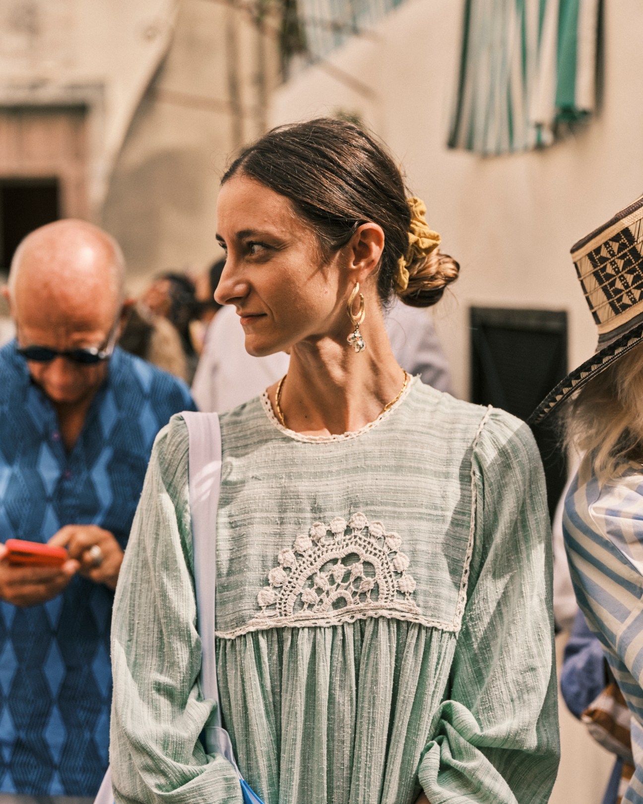 Woman in sage green dress with lace detail and pearl earrings at outdoor art festival