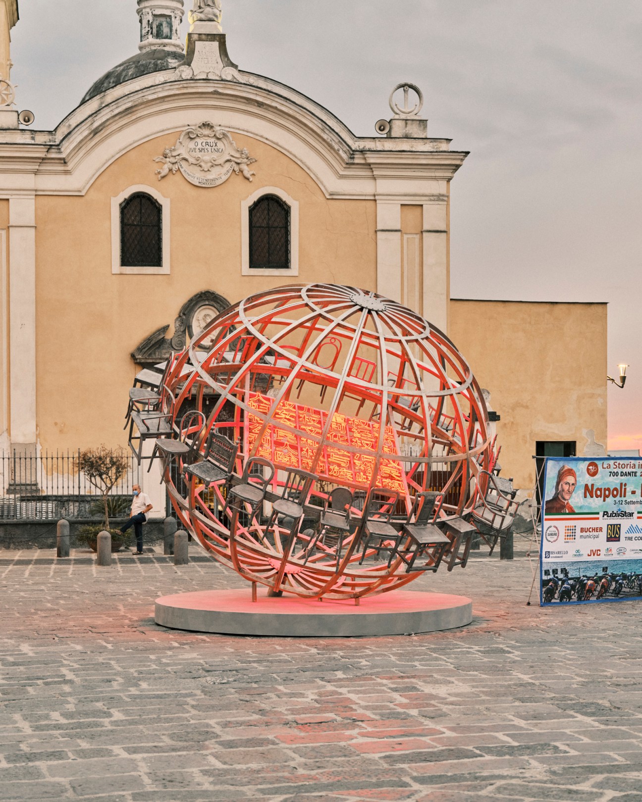 Chen Zhen's large spherical metal sculpture with chairs attached displayed in a church piazza