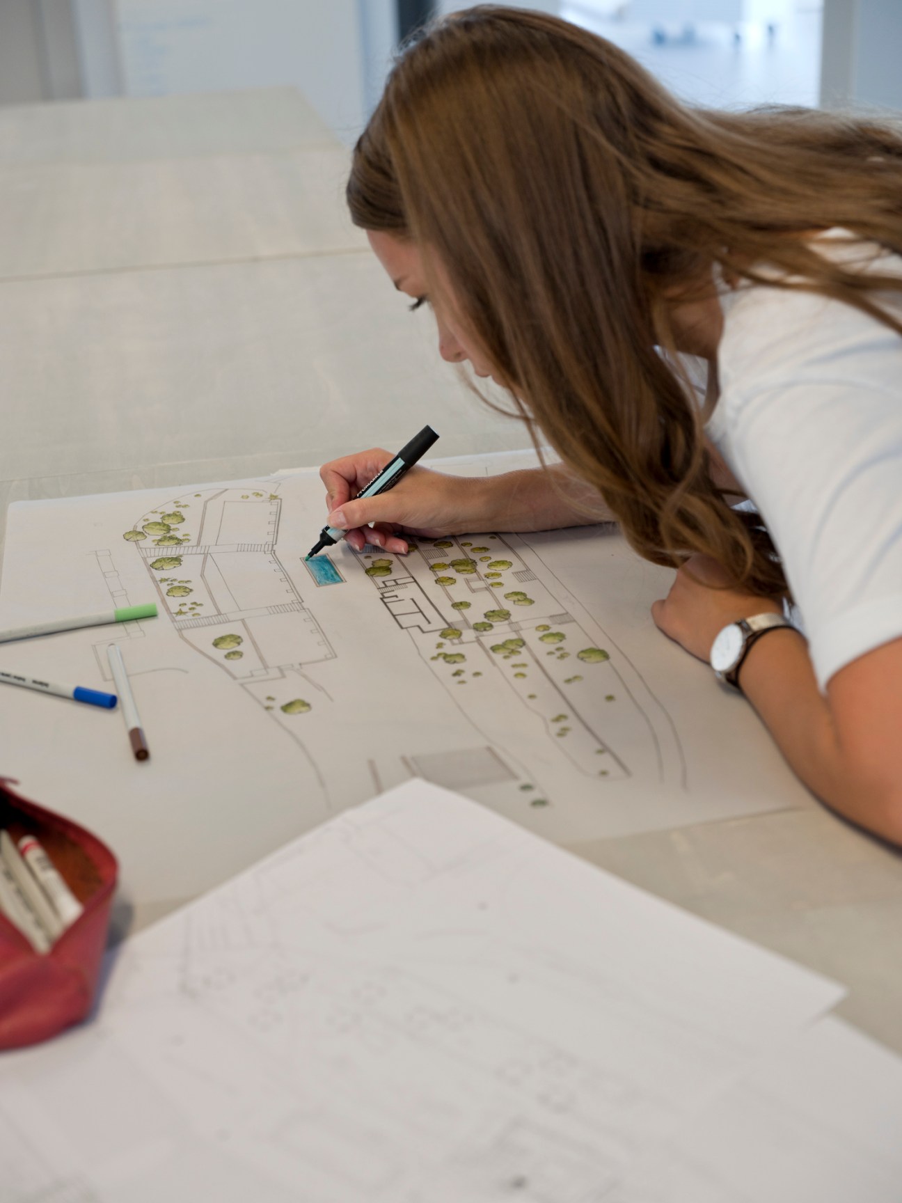 Student sketching architectural landscape design with markers on paper at Camondo Méditerranée.