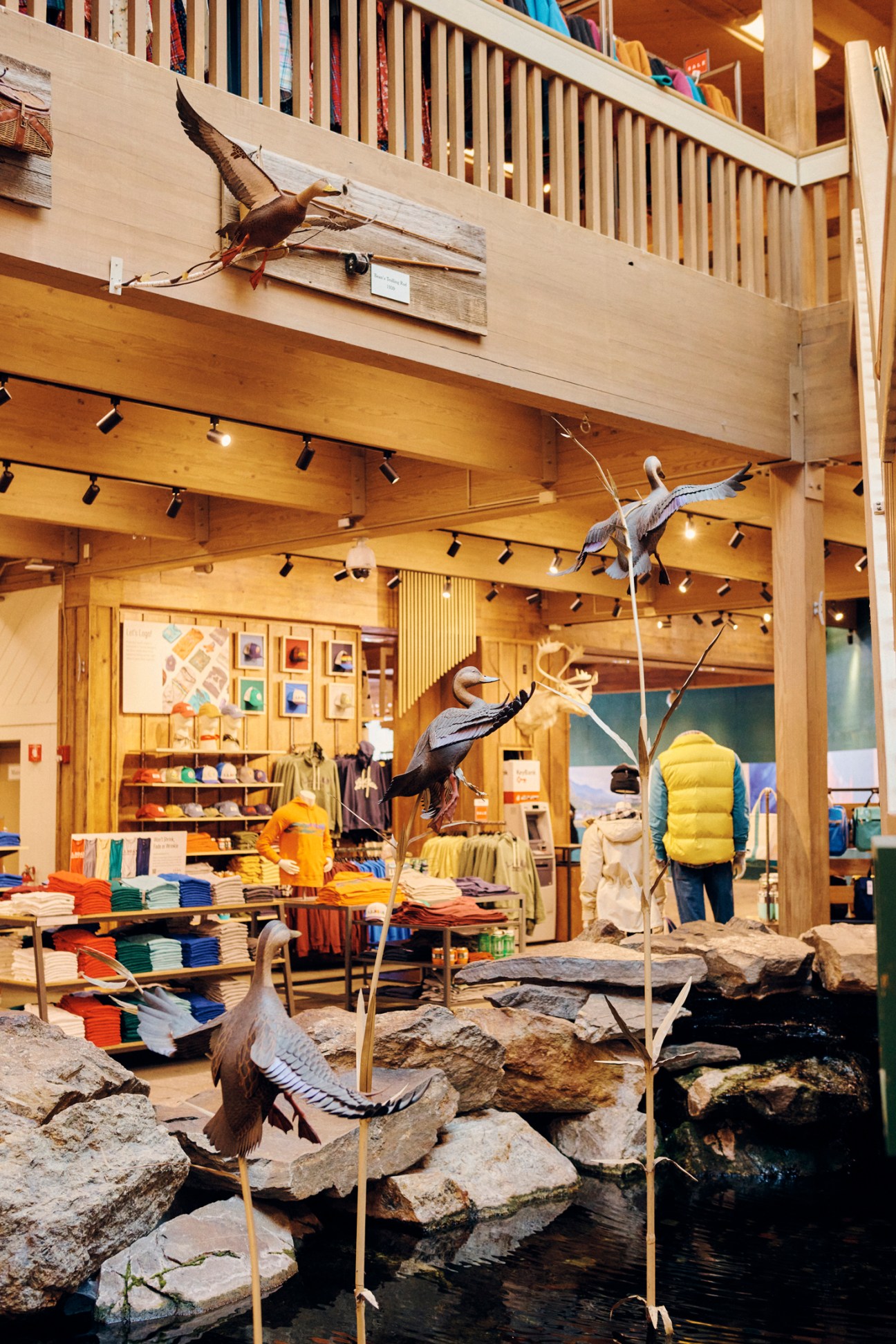 Interior of LL Bean flagship store in Maine with wooden railings, taxidermy birds, and outdoor gear displays