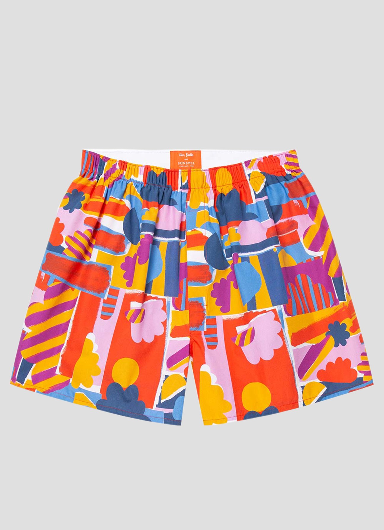 Sunspel swim shorts in colorful kaleidoscopic pattern featuring red, blue, yellow, pink and purple geometric shapes and cloud motifs.