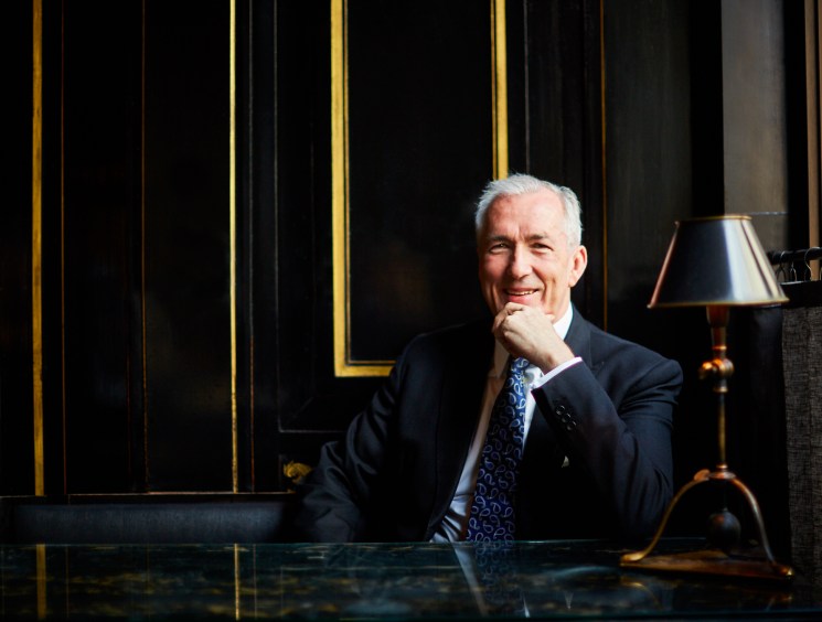 Jeremy King, restaurateur and co-founder of Corbin & King, seated at a desk in an elegantly designed interior with black paneling and gold trim.