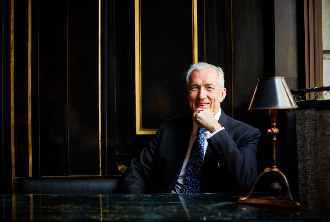 Jeremy King, restaurateur and co-founder of Corbin & King, seated at a desk in an elegantly designed interior with black paneling and gold trim.
