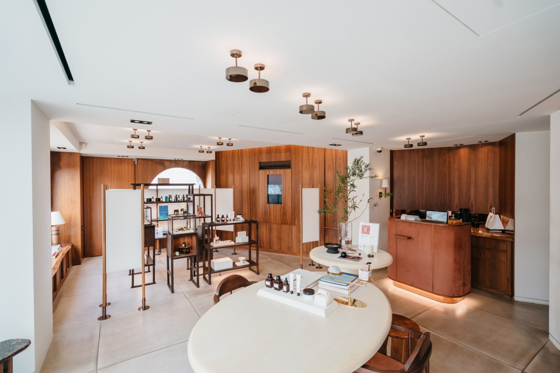 Modern retail interior with wood paneling, white curved counter, pendant lighting, and skincare products displayed